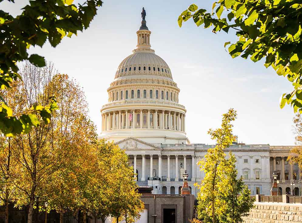 View of the Capitol Building in Washington DC Warmly Lit by an Afternoon Autumnal Sun. Some Colorful Trees are in Foreground.