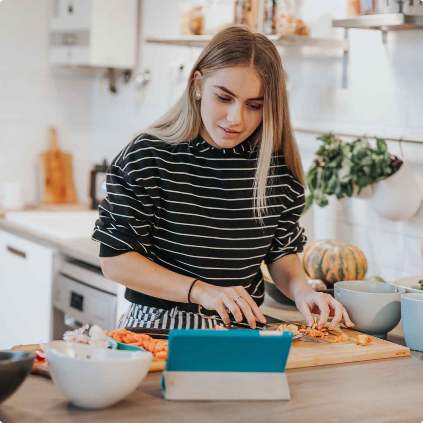 Woman using digital tablet in kitchen while preparing food