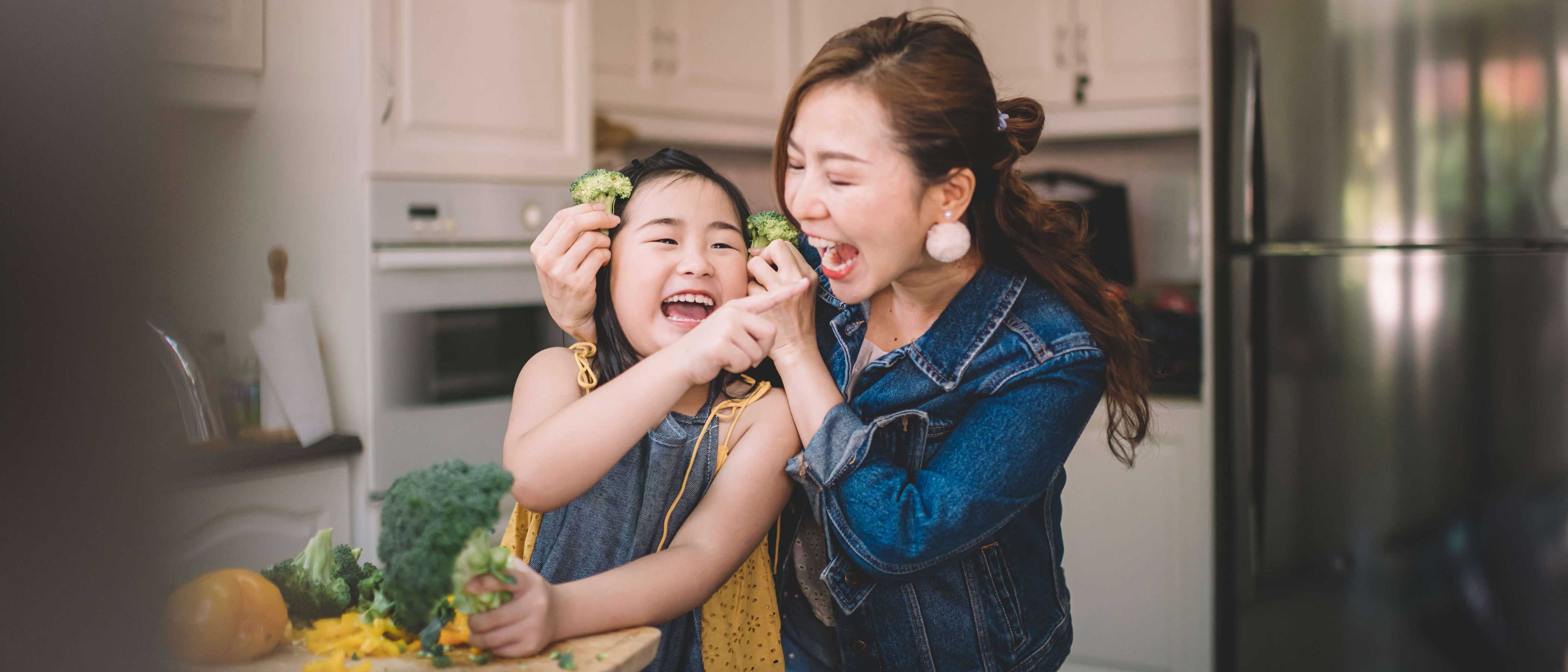 Mother and daughter in kitchen having fun while preparing food